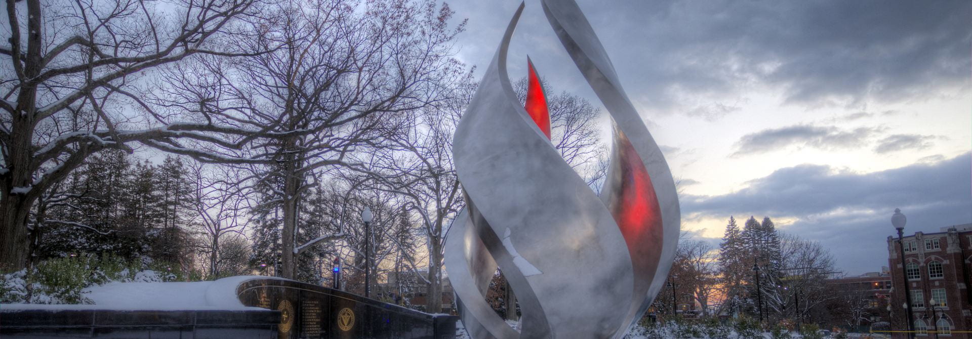 Silver Flame Statue with Red Glowing Light and Snow on Bare Trees.
