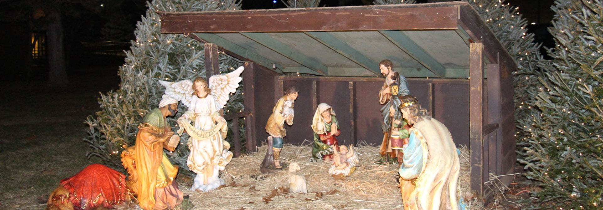 Manger Scene with Ceramic Statues and Lighted Trees.
